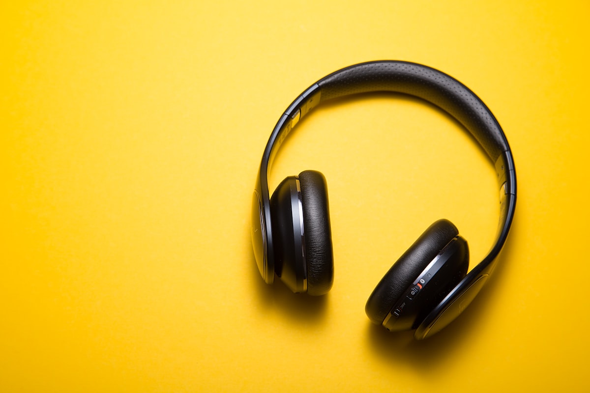 Person listening to long-form audio content through headphones at a desk