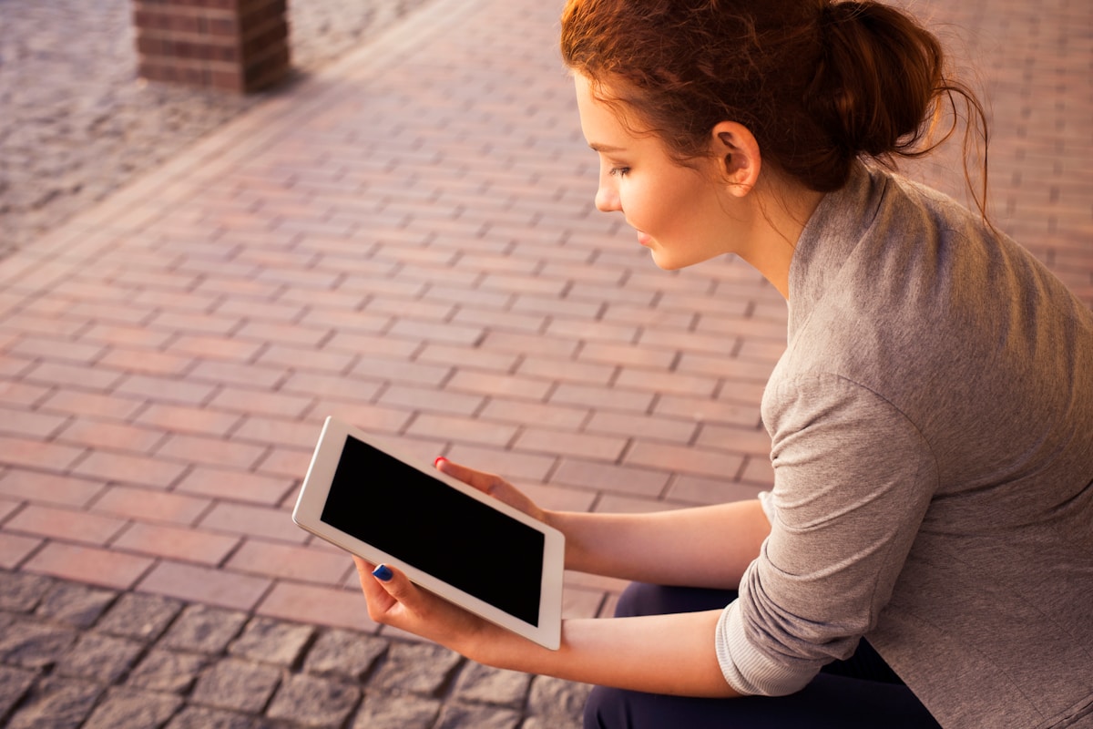 Person reading and listening to content on an iPad tablet outdoors