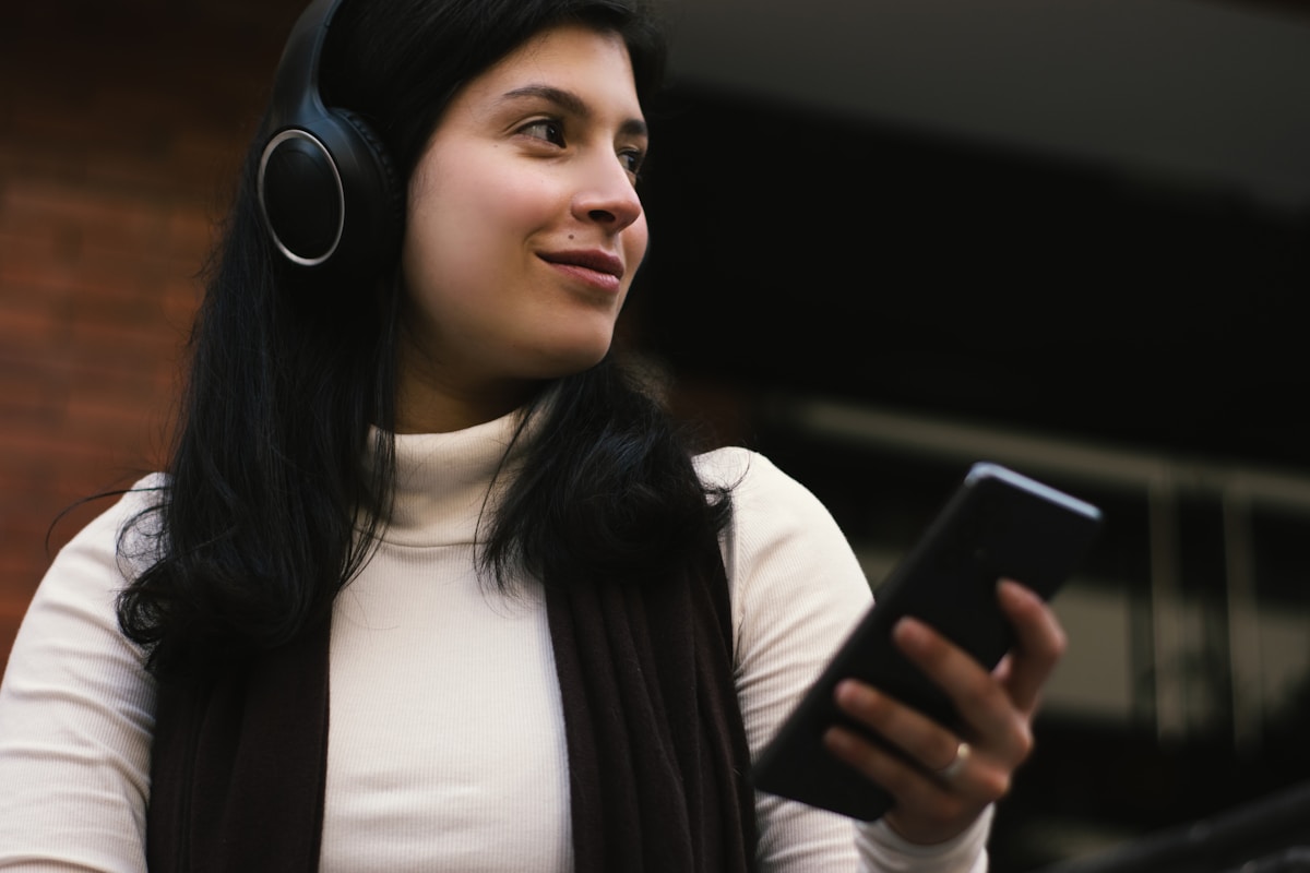 Woman listening to text read aloud through headphones while holding her iPhone